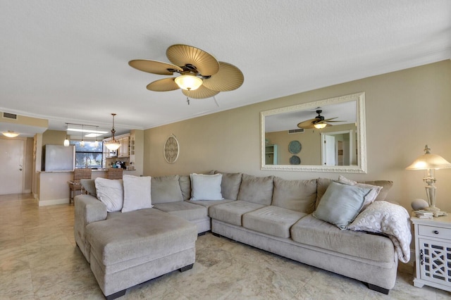 living room featuring ceiling fan, ornamental molding, and a textured ceiling