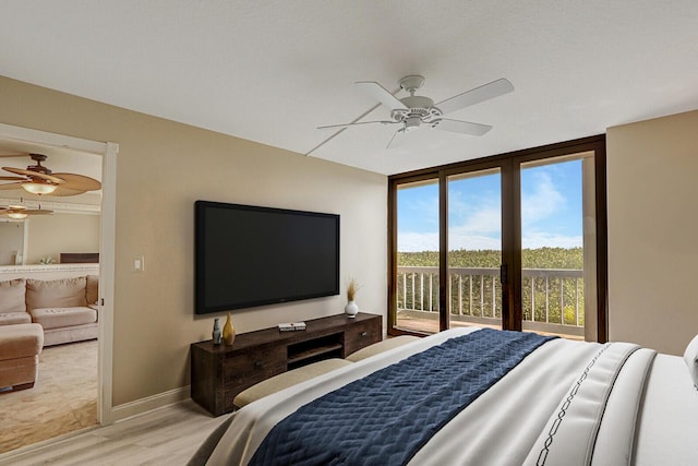 bedroom with ceiling fan, wood-type flooring, access to exterior, and a wall of windows