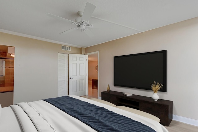 bedroom with a ceiling fan, wood finished floors, baseboards, visible vents, and a closet