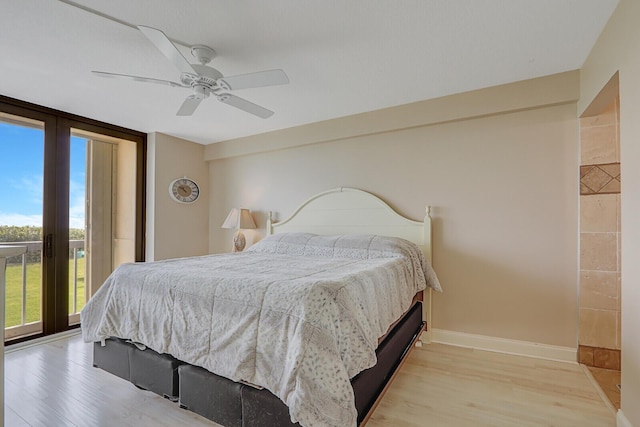 bedroom featuring access to outside, expansive windows, ceiling fan, and light wood-type flooring