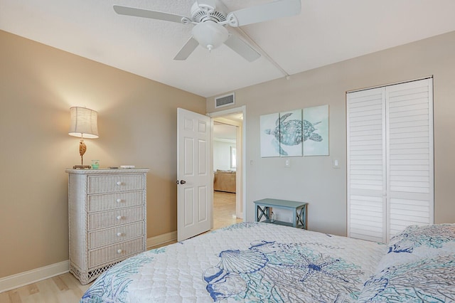 bedroom featuring a ceiling fan, wood finished floors, visible vents, baseboards, and a closet