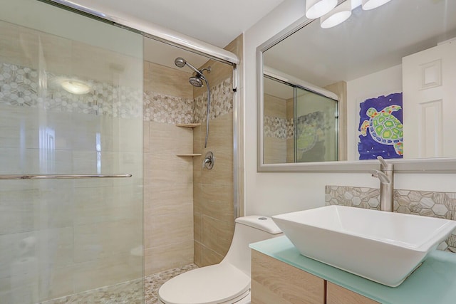 bathroom featuring vanity, a shower with shower door, and toilet