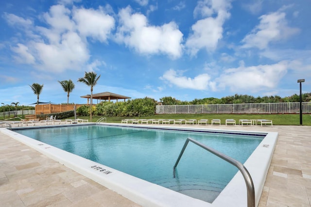 pool with a patio, a yard, and fence