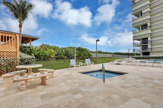 view of pool featuring fence, a lawn, a community hot tub, and a patio area