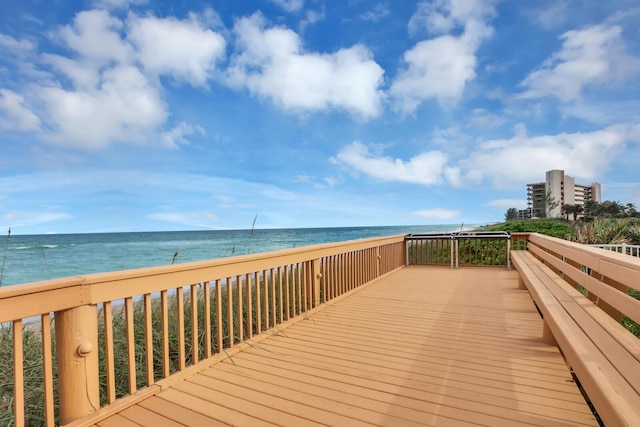 wooden terrace featuring a water view and a view of the beach