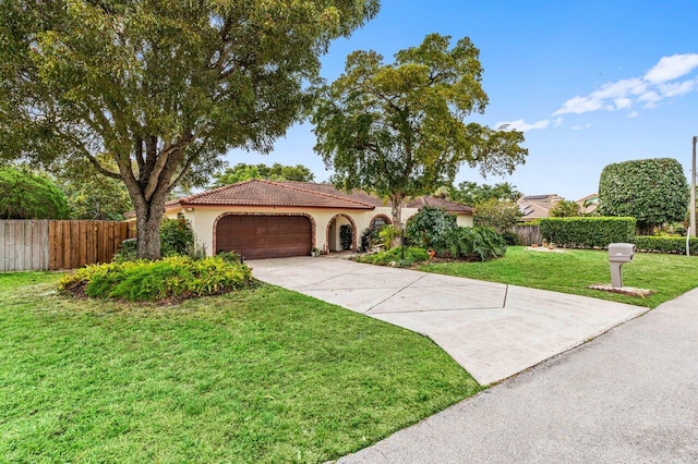 mediterranean / spanish home featuring a tile roof, fence, a front lawn, and stucco siding