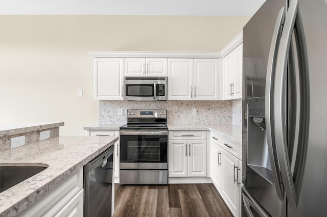 kitchen featuring appliances with stainless steel finishes, dark hardwood / wood-style floors, light stone countertops, decorative backsplash, and white cabinets