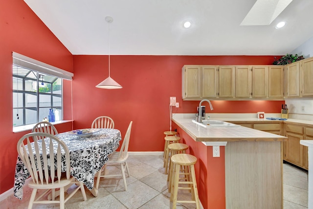 9158 Heathridge Dr, West Palm Beach, FL 33411 - kitchen featuring sink, a breakfast bar area, lofted ceiling with skylight, decorative light fixtures, and light brown cabinets