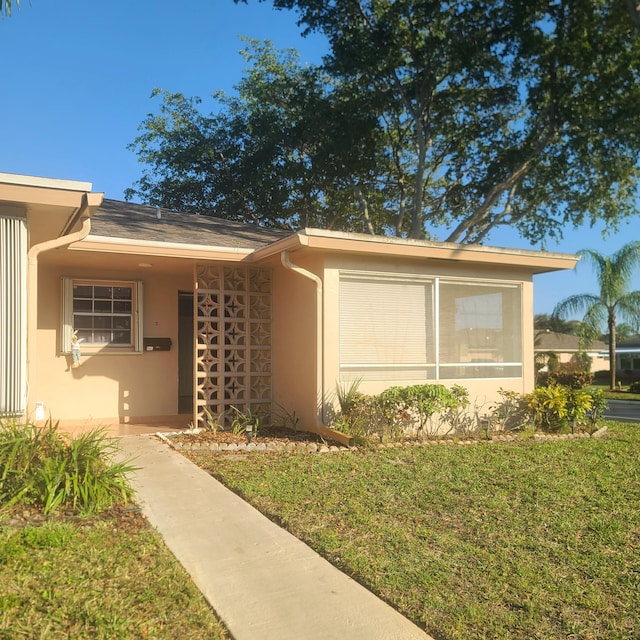 view of front of house with a sunroom and a front yard