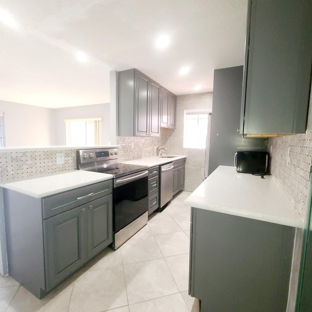 kitchen with sink, light tile patterned floors, appliances with stainless steel finishes, gray cabinetry, and tasteful backsplash