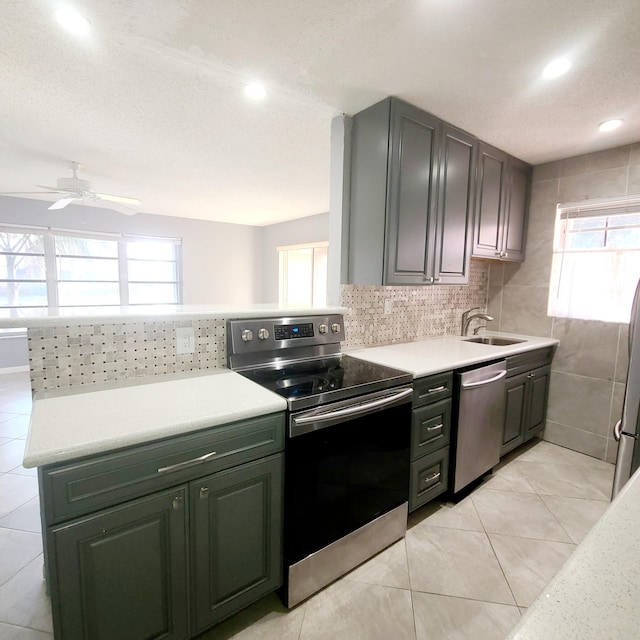 kitchen featuring light tile patterned flooring, tasteful backsplash, sink, ceiling fan, and stainless steel appliances