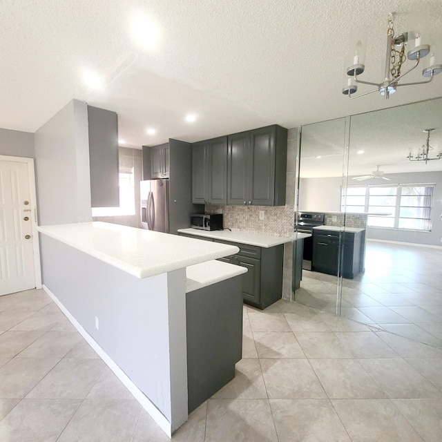 kitchen featuring tasteful backsplash, light tile patterned floors, appliances with stainless steel finishes, a kitchen island, and ceiling fan