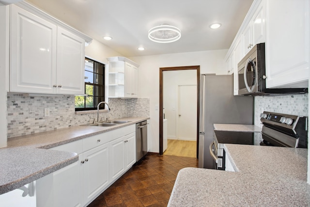 kitchen with appliances with stainless steel finishes, sink, white cabinets, and light stone counters