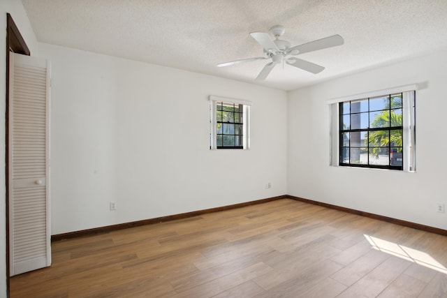 spare room with ceiling fan, light hardwood / wood-style flooring, and a textured ceiling