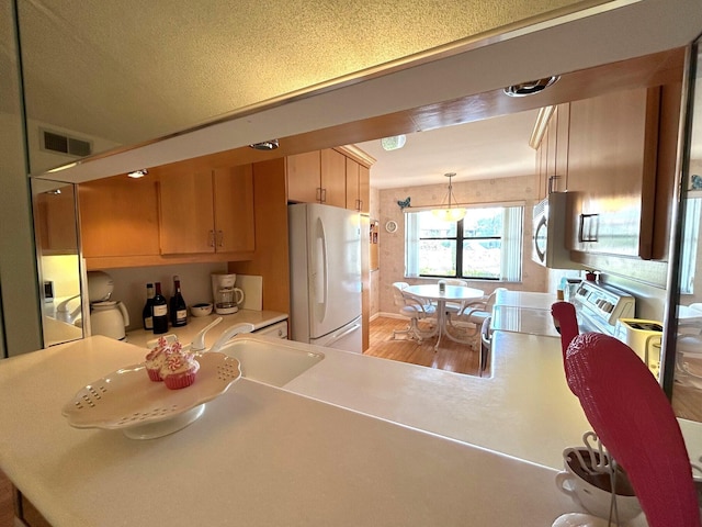 kitchen featuring white refrigerator, kitchen peninsula, and pendant lighting