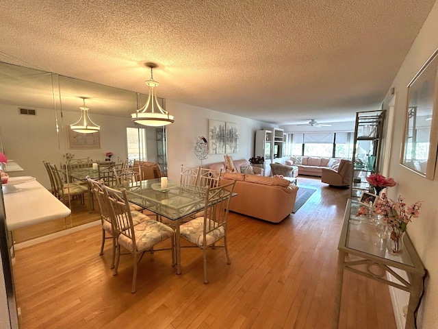 dining space with ceiling fan, hardwood / wood-style floors, and a textured ceiling