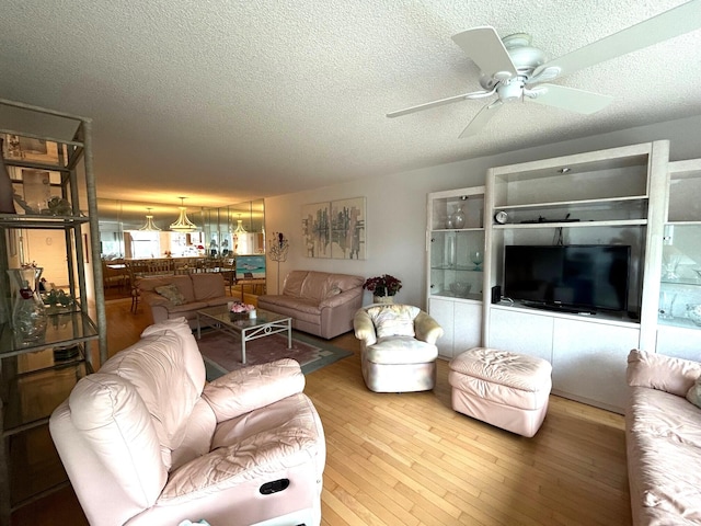 living room featuring a textured ceiling, wood-type flooring, and ceiling fan