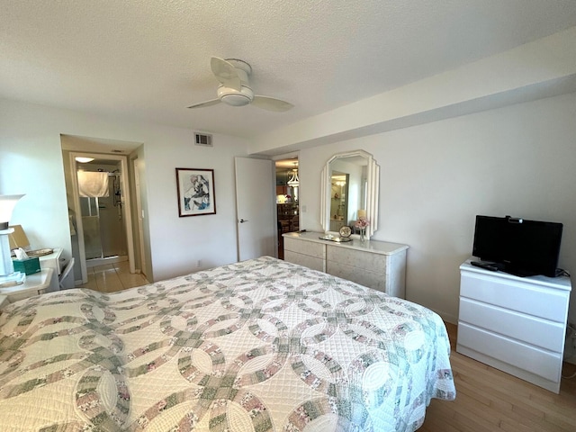 bedroom featuring ceiling fan, light hardwood / wood-style flooring, and a textured ceiling