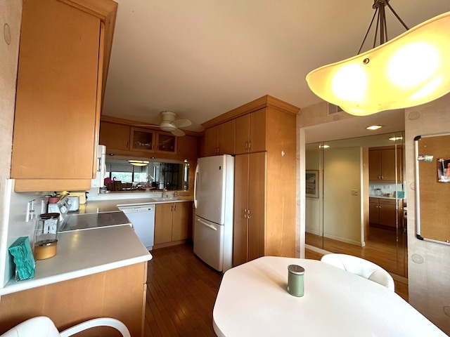 kitchen with white appliances, a kitchen bar, dark hardwood / wood-style flooring, decorative light fixtures, and kitchen peninsula