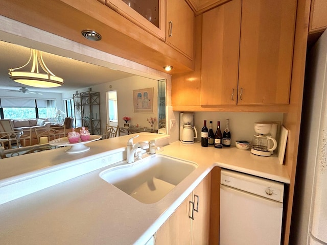 kitchen featuring white dishwasher, kitchen peninsula, sink, and decorative light fixtures