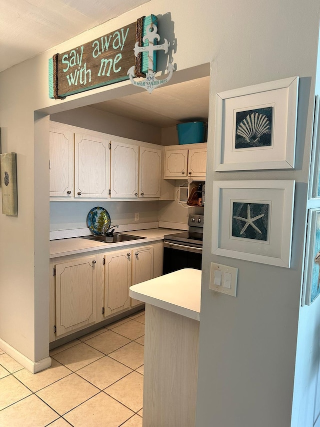 kitchen featuring sink, light tile patterned floors, and stainless steel range with electric cooktop