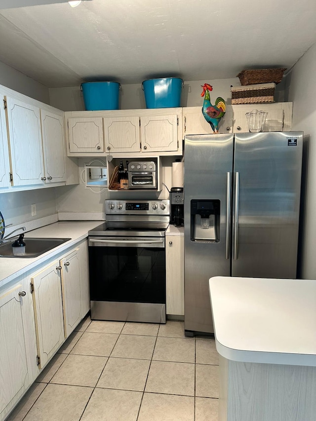 kitchen with white cabinetry, appliances with stainless steel finishes, sink, and light tile patterned floors