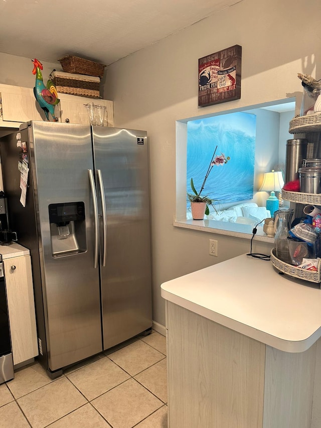 kitchen with stainless steel refrigerator with ice dispenser, stove, light tile patterned flooring, and light brown cabinets