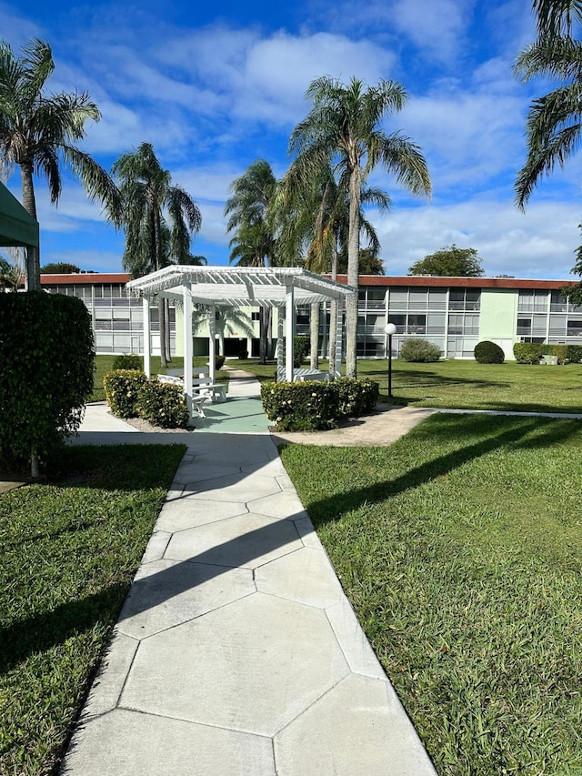 view of community featuring a pergola and a lawn