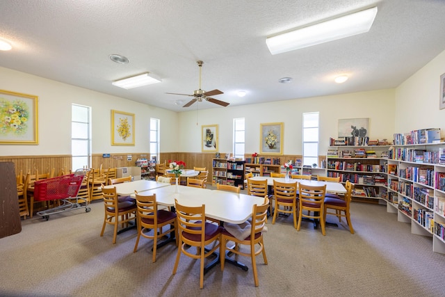 dining area with wooden walls, a textured ceiling, and carpet flooring