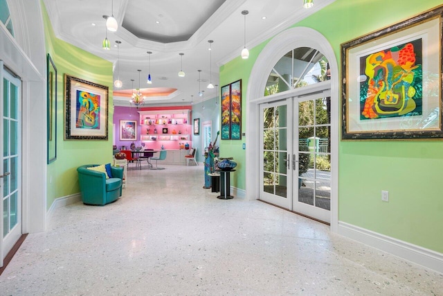 interior space with baseboards, a raised ceiling, french doors, crown molding, and speckled floor