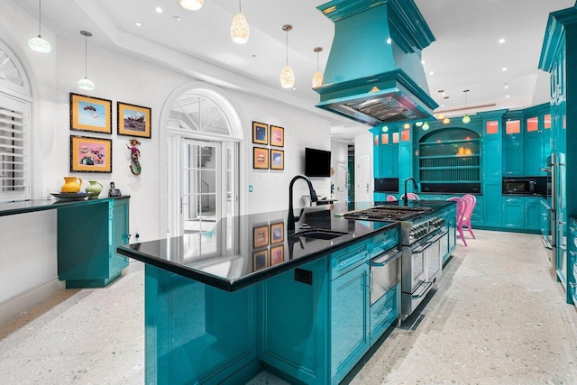 kitchen with blue cabinets, island range hood, a sink, dark countertops, and decorative light fixtures