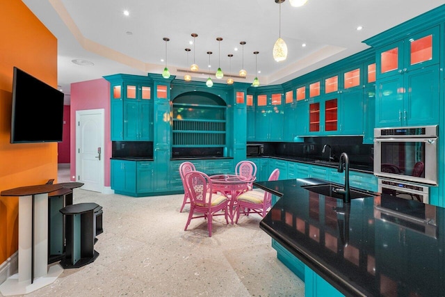 kitchen featuring blue cabinets, dark countertops, pendant lighting, and glass insert cabinets