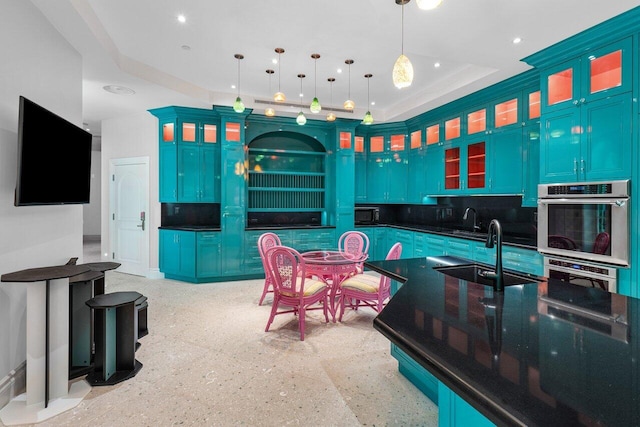 kitchen featuring hanging light fixtures, blue cabinetry, dark countertops, and glass insert cabinets