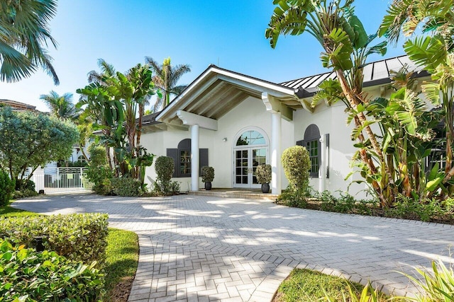 exterior space featuring a standing seam roof, metal roof, fence, and stucco siding