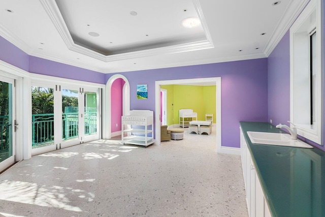 interior space with crown molding, baseboards, a raised ceiling, and a sink