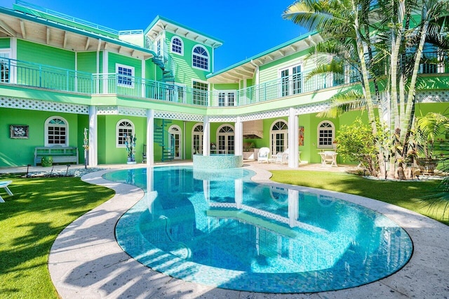 outdoor pool featuring a patio, a lawn, and french doors