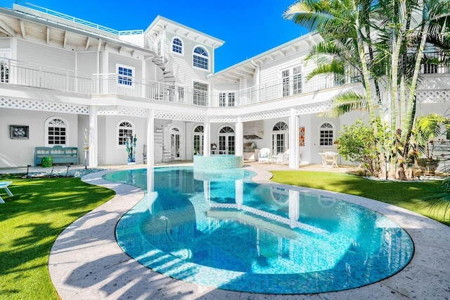 back of house featuring french doors, a lawn, a balcony, and an outdoor pool