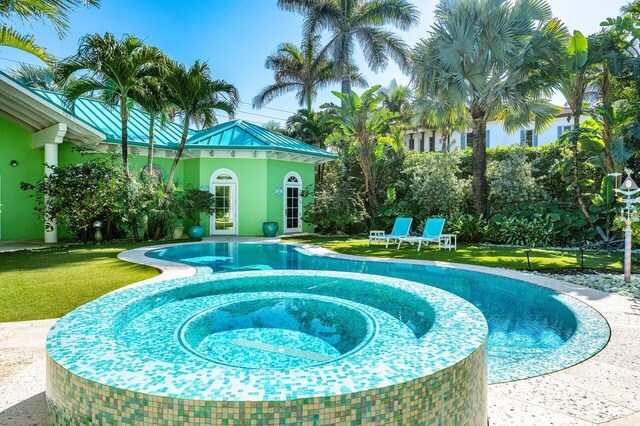 view of swimming pool with a pool with connected hot tub and a lawn