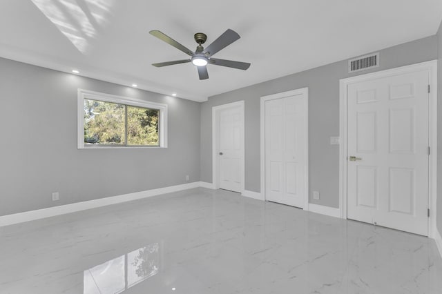 unfurnished bedroom featuring two closets and ceiling fan