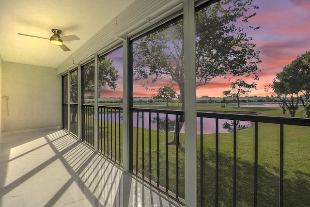 unfurnished sunroom featuring a water view and ceiling fan