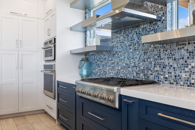 kitchen with open shelves, wall chimney range hood, blue cabinets, and stainless steel gas cooktop