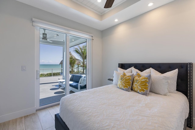 bedroom featuring baseboards, a tray ceiling, recessed lighting, access to exterior, and light wood-style floors