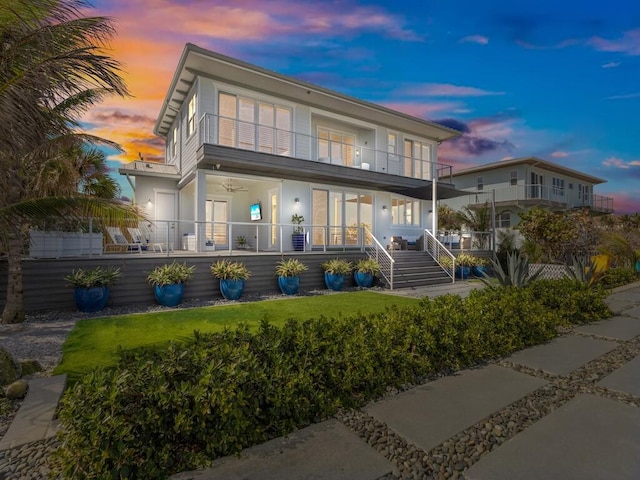 rear view of property featuring a yard, a balcony, and covered porch