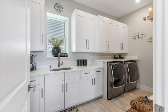 clothes washing area featuring cabinet space, independent washer and dryer, wood finish floors, and a sink