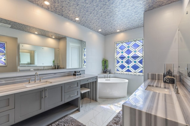 full bath featuring vanity, recessed lighting, marble finish floor, and a freestanding bath