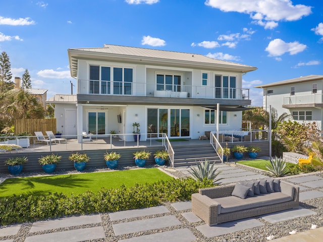 back of property featuring a balcony, fence, a patio area, a lawn, and metal roof