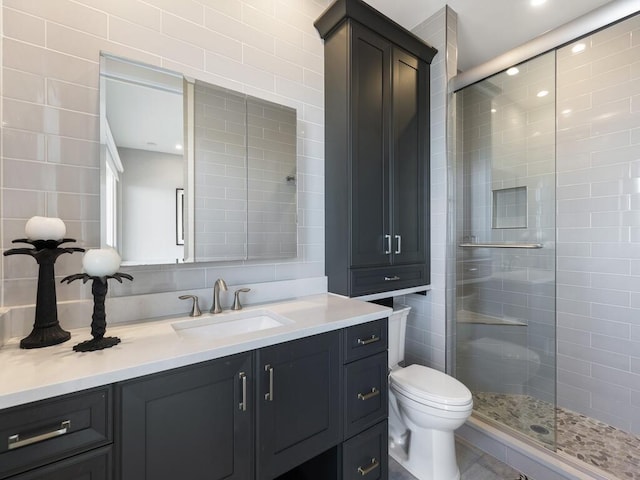 full bathroom with vanity, a shower stall, toilet, and tile walls