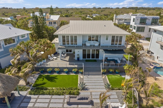 rear view of property with stairway, a balcony, a fenced backyard, a patio area, and metal roof