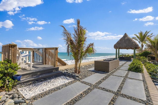 view of patio / terrace with a gazebo, a beach view, a water view, and an outdoor hangout area