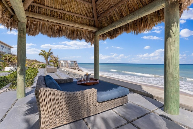 view of patio / terrace featuring a gazebo, a water view, and a beach view